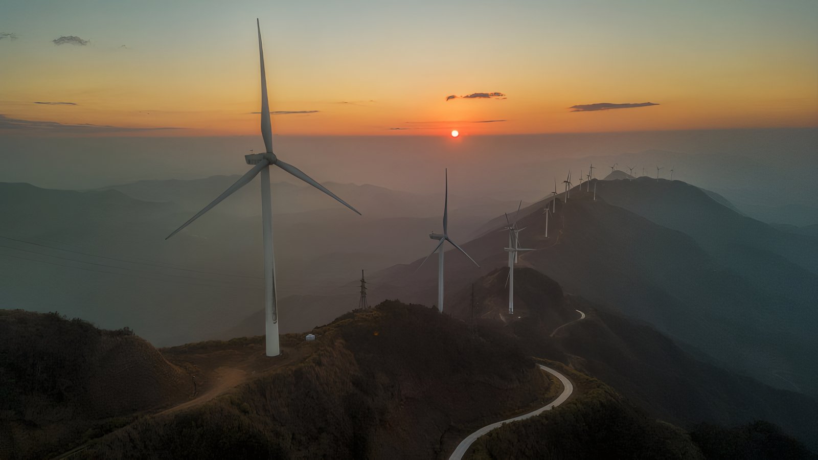 Sunset wind farm spread across mountainous terrain in golden hour light, evoking long-horizon strategy