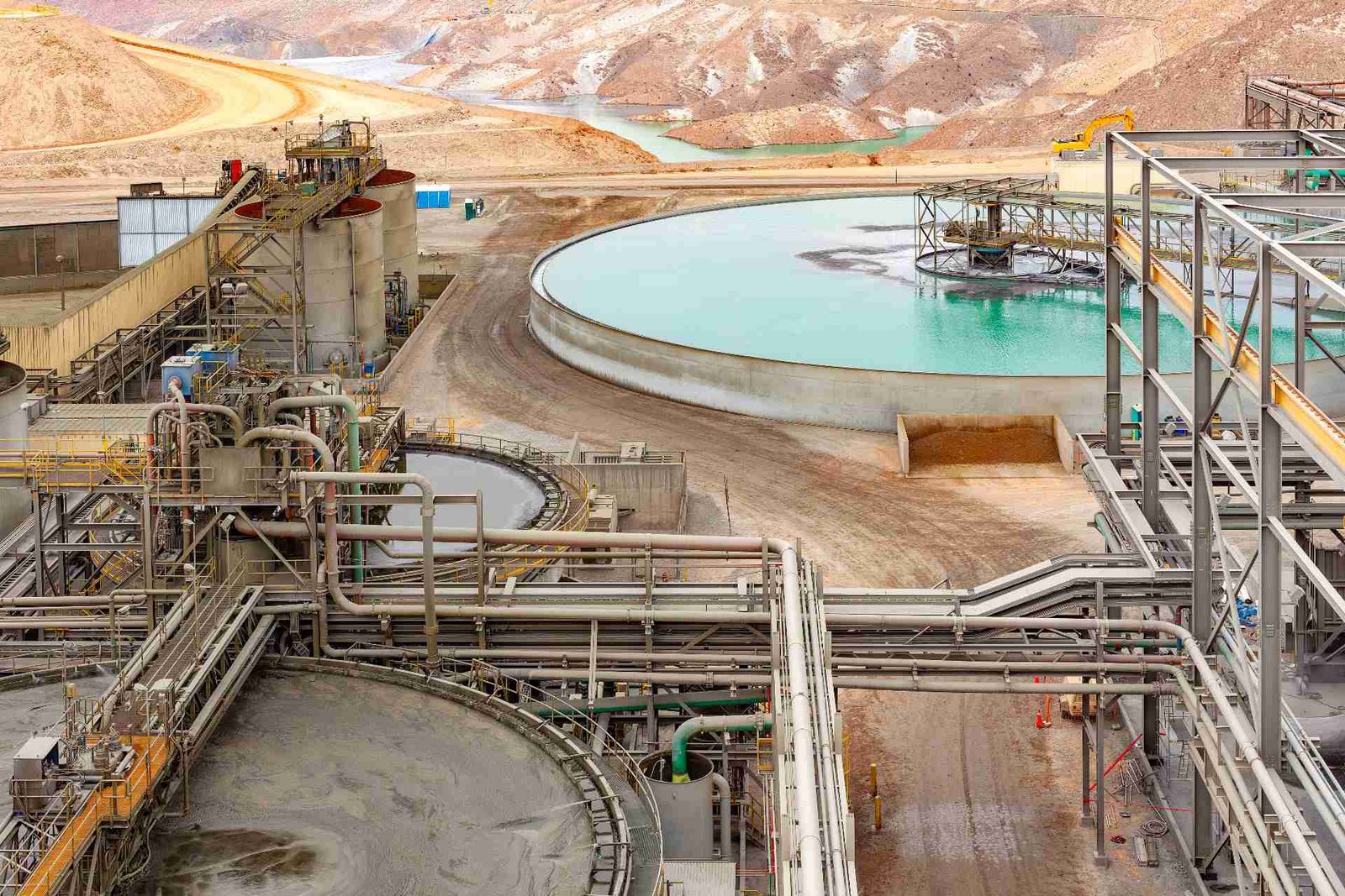 Large-scale mining operation with processing equipment and turquoise settling ponds